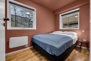 a bedroom with a bed and two windows at Northstay - The Urban City Haven in Tromsø