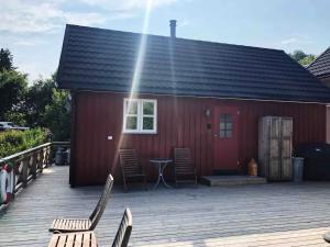 a red building with chairs and a table on a deck at Nora's Waterfront Cabin in Svolvær +13 photos