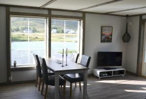 a dining room with a table and chairs and a television at Fredvang Seahouse, apartment A in Fredvang
