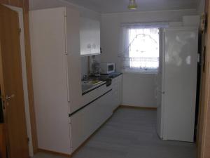una cucina bianca con lavello e frigorifero di Nydelig leilighet i første etage. a Sund