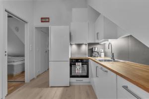 a kitchen with white cabinets and a stove top oven at Modern loft apartment in Tromsø City Center in Tromsø