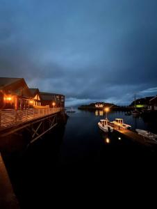 a dock with a boat in the water at night at Amazing waterfront rorbu (free car-charging) in Stamsund