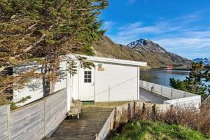 a white building on a dock next to a body of water at Panoramic seaview cabin for two persons by the sea in Hovdan +6 photos