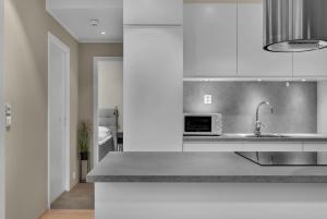 a white kitchen with a sink and a microwave at Northstay - King's Park in Tromsø +10 photos