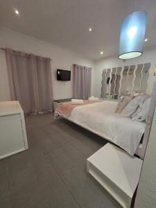 a bedroom with a large white bed and a tv at AL Manas Pereira in Castro Marim
