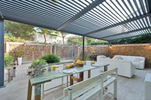 Un patio con una pérgola de madera con mesa y sillas. en Bonita casa adosada en esquina, en Marbella