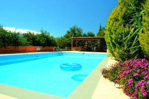 a large swimming pool in a yard with purple flowers at Anna-Malai Penthouse in Megála Khoráfia