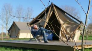 a man sitting in front of a tent at Camping à la ferme - Hébergements insolites in Cerisy-la-Forêt