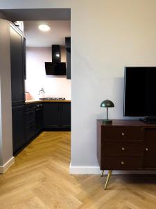 a kitchen with black cabinets and a television on a dresser at Apartament w Centrum z widokiem na Stare Miasto Zamość in Zamość