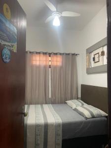 a bedroom with a bed with a ceiling fan at Guest House do Magoo in Arraial do Cabo