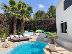 a swimming pool with two lounge chairs and palm trees at Villa Esterel Plage in Saint-Raphaël