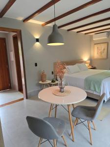 a bedroom with a bed and a table and chairs at Confraria da Prata Flats in Pirenópolis