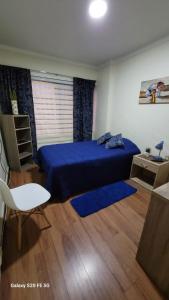 a bedroom with a blue bed and a wooden floor at Hostal Donde Gabriel in Chillán