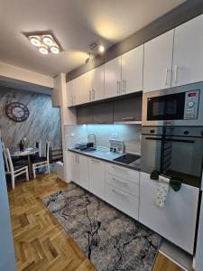 a kitchen with white cabinets and a stove top oven at Daluxst apartman in Vrnjačka Banja