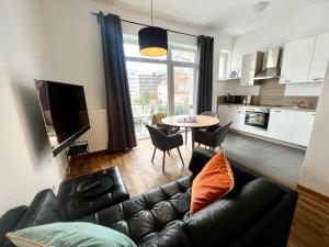 a living room with a leather couch and a table at Cooles City-Appartment - Balkon in Bayreuth