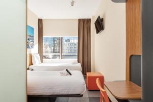 una camera d'albergo con due letti e una scrivania di easyHotel The Hague Scheveningen Beach a Scheveningen Altre 63 foto