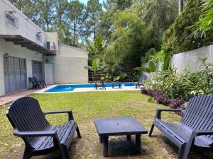 two chairs and a table in a yard with a pool at Casa de Huespedes Guacaras in Santa Ana