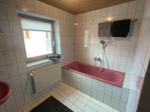 a bathroom with a pink tub and a window at Ferienwohnung im Alpenvorland am Lech in Apfeldorf
