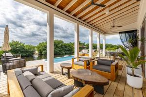 eine Terrasse mit einem Sofa, Tischen und einem Pool in der Unterkunft Vista de Azul and The Pool Club at Mahogany Bay in San Pedro