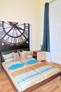 a large bed in a bedroom with a clock on the wall at Frank & Fang Apartments in Budapest