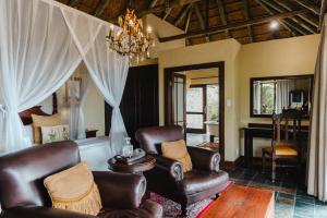 a living room with leather chairs and a chandelier at Hitgeheim Country Lodge in Addo