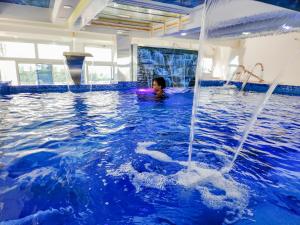 a child in a swimming pool with water coming out at Hôtel Résidence Saint James Maguerita in Douala