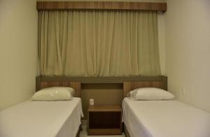 two beds in a room with a window at Praias do Lago in Caldas Novas