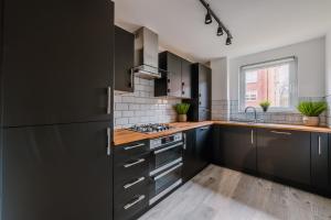 a kitchen with black cabinets and a sink at ComfySleep Apartments in Glasgow