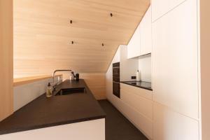 a kitchen with white cabinets and a black counter top at Beerenhus in Au im Bregenzerwald +11 photos