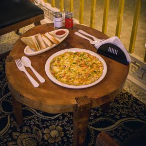 a table with a pizza and some bread on it at PalPenzy - Bespoke Premium Stay in Srinagar