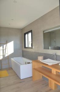 a bathroom with a white tub and a sink at Belle maison avec piscine à débordement chauffée in Barjac
