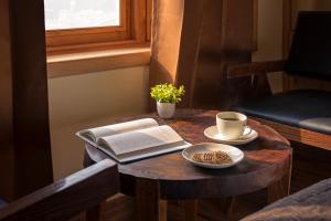 a table with a book and a cup of coffee at PalPenzy - Bespoke Premium Stay in Srinagar