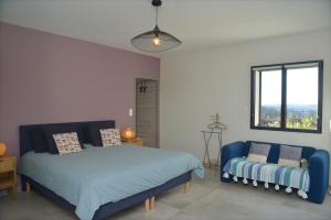 a bedroom with a bed and a couch and a window at Belle maison avec piscine à débordement chauffée in Barjac +26 photos