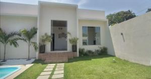 a white house with a yard and a swimming pool at Casa Veraneio Barra Jacuipe in Camaçari