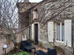 an old stone house with two chairs and a door at gîte La Ferrandière Berson Blaye Bordeaux Gironde in Berson