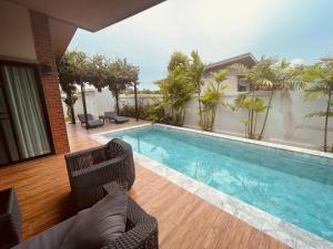a swimming pool with two chairs and a house at Anchan Gardens Pool Villa 23 in Hua Hin