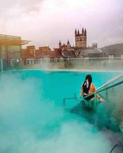 a woman laying on a surfboard in a pool of water at Self contained 1 bed house v near centre, parking in Bath