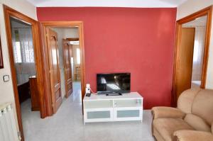 a living room with a tv on a red wall at Villa de hermanos in Villardefrades