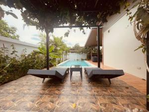 a pool with two chairs and a table in front of a house at Anchan Gardens Pool Villa 23 in Hua Hin