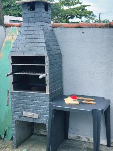 a brick oven with a table next to a wall at Casa Bali Beira Mar - Sesc Bertioga in Bertioga