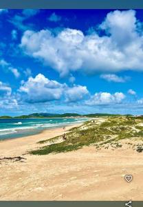 une plage avec des gens sur le sable et l'océan dans l'établissement Cantinho do sossego, à Cabo Frio