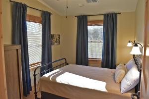 een slaapkamer met een bed en twee ramen met blauwe gordijnen bij Johnson's Shut-ins State Park in Monterey