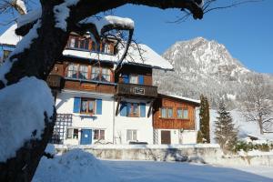 a building in the snow with a mountain at Haus Daheim in Bad Hindelang