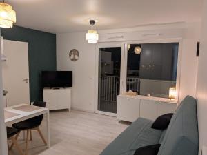 a living room with a couch and a table and a television at Studio Les Capucines in Bretteville-sur-Odon