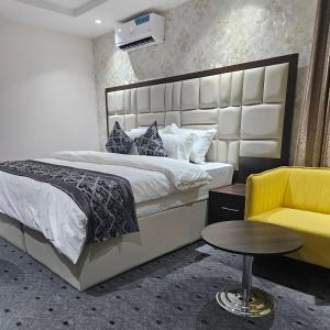 a bedroom with a large bed and a yellow chair at Anibex Luxe Apartment in Abuja