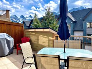 een patio met een tafel en een blauwe parasol bij Fire Mountain Lodge in Canmore