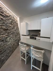 a kitchen with a table and two chairs and a stone wall at Un balcone sul lago in Torno