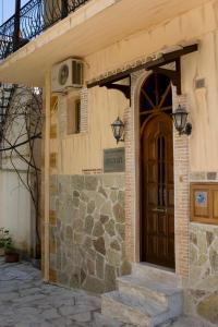a building with a wooden door and a stone wall at Hotel Tourist in Parga
