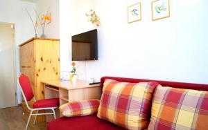 a living room with a red couch and a desk at Fürstenhof Landgasthaus & Hotel in Erfurt