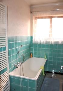 a bath tub in a bathroom with green tiles at Maison enchanteur à Berrwiller avec jardin paisible in Berrwiller
